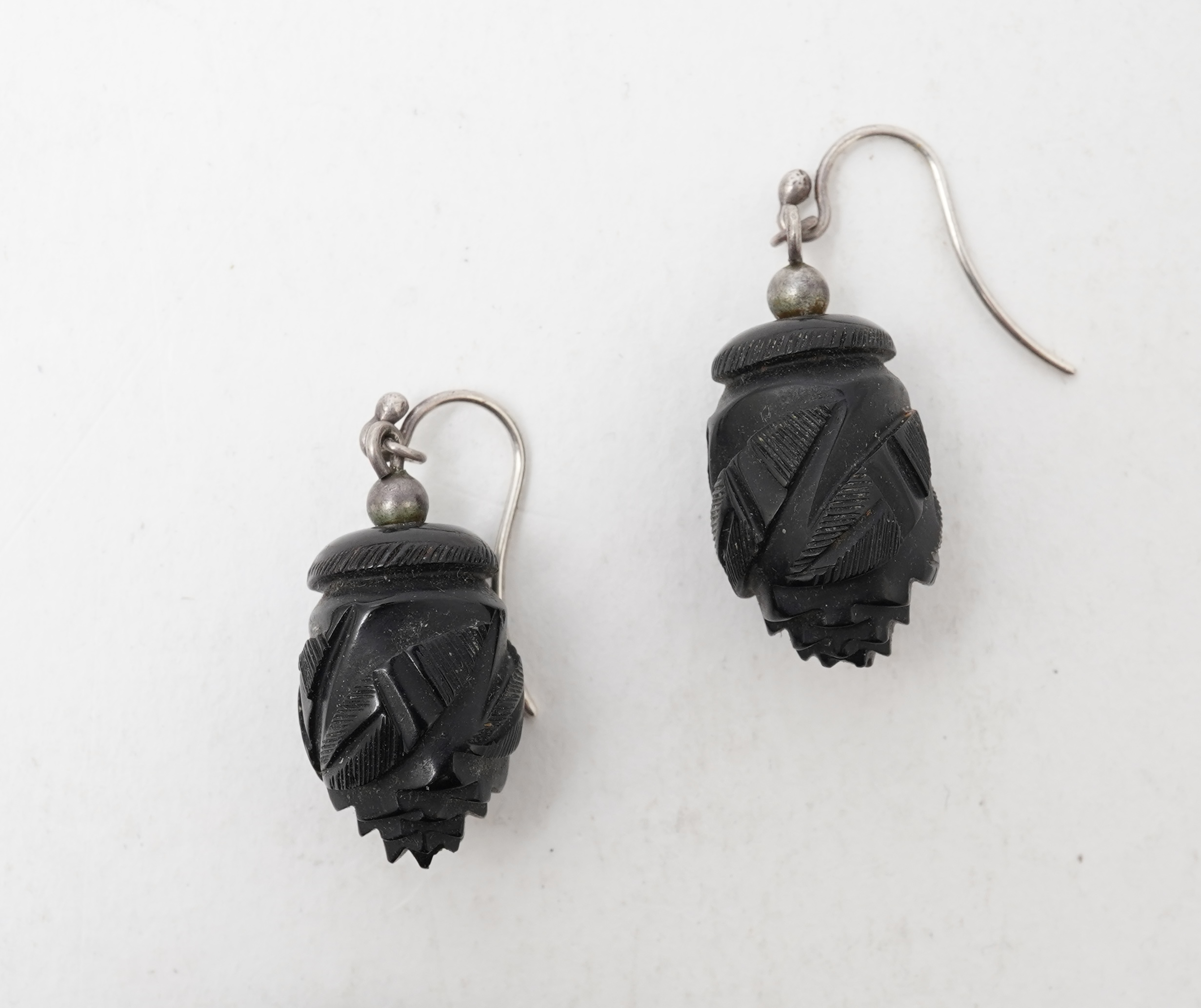 A collection of jewels, comprising: a moulded bog oak brooch depicting a hand holding a posy, length 7.4cm; a carved jet brooch depicting a Gothic ruin, possibly part of Whitby Abbey; a necklace composed of polished pane